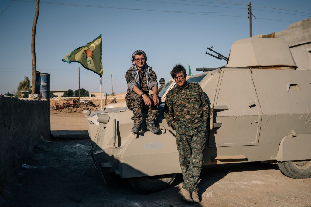 Lucas Chapman, left, and Brace Belden, U.S. volunteers with the People’s Protection Units, or YPG, pose for a portrait next to a homemade armored vehicle in a rear base near Tal Samin, Syria. (Alice Martins/For The Washington Post)